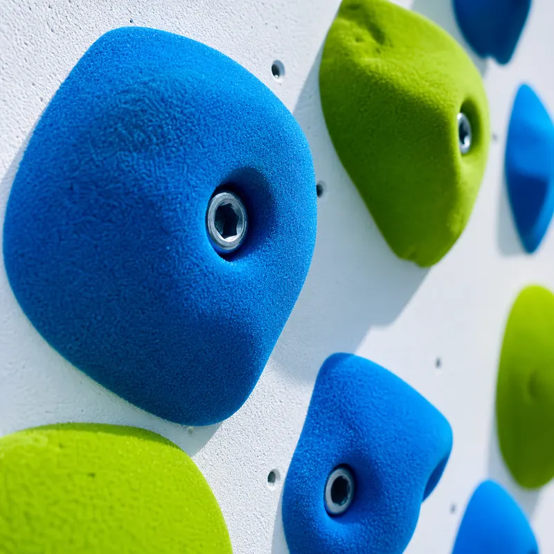 Detalle de las presas de escalada del muro de trepa, en azul y verde lima